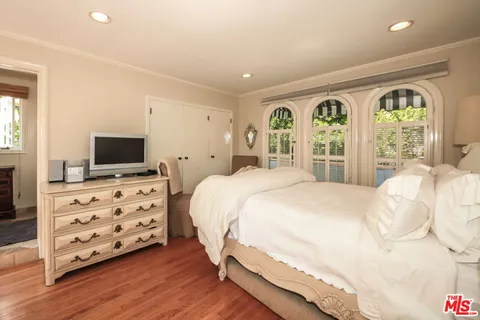 a bedroom with a bed a flat screen tv and a large window with the garden view