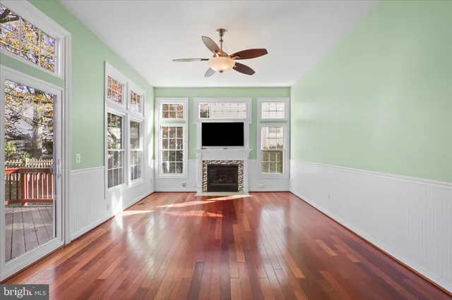 a view of a livingroom with a fireplace a ceiling fan and windows