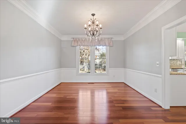 a view of empty room with wooden floor and chandelier