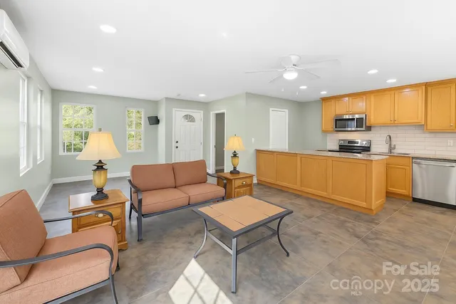 a kitchen with stainless steel appliances granite countertop a sink a stove a refrigerator cabinets and living room view