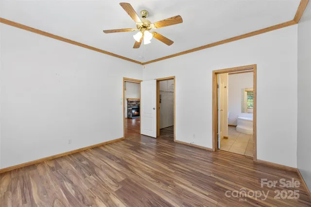 an empty room with wooden floor and a ceiling fan