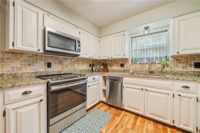 a kitchen with granite countertop white cabinets stainless steel appliances and a sink