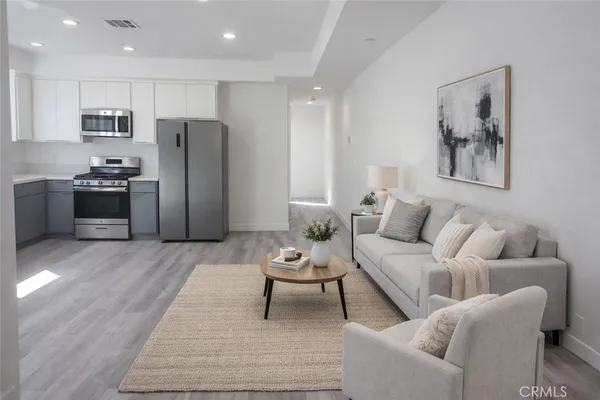 a living room with stainless steel appliances lots of furniture and a rug