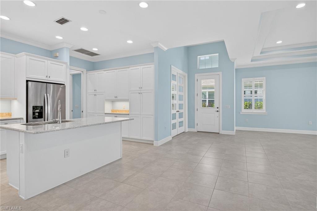 8813 Yucatan Court Naples, FL 34113 - Photo 14 of 43 Kitchen featuring recessed lighting, white cabinetry, stainless steel fridge with ice dispenser, light quartz countertops, and a center island with sink