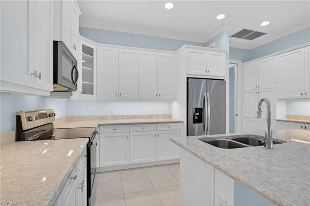 a large white kitchen with a sink and stainless steel appliances