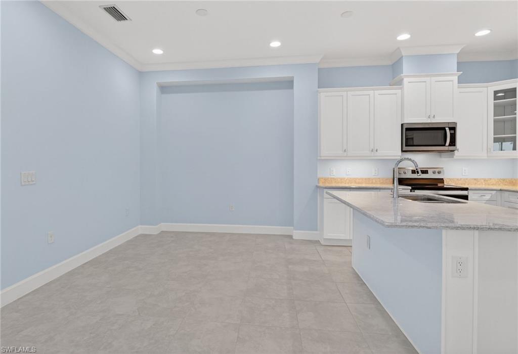 8813 Yucatan Court Naples, FL 34113 - Photo 19 of 43 Dining Area featuring white cabinets, glass insert cabinets, light stone countertops, stainless steel appliances, and recessed lighting