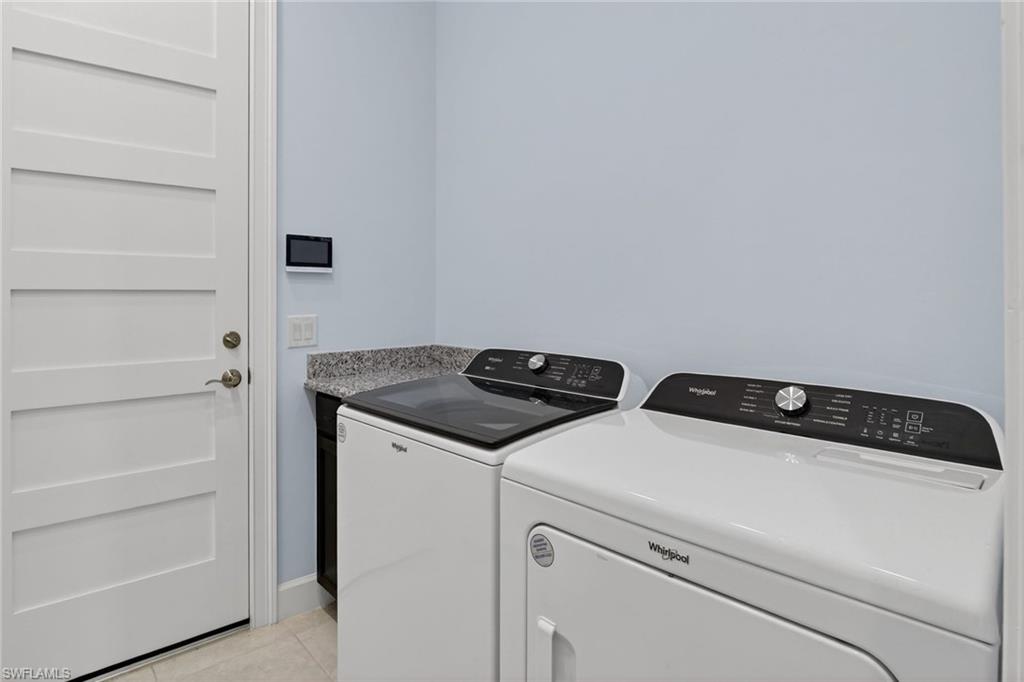 8813 Yucatan Court Naples, FL 34113 - Photo 30 of 43 Laundry area with washing machine and dryer and light tile patterned flooring