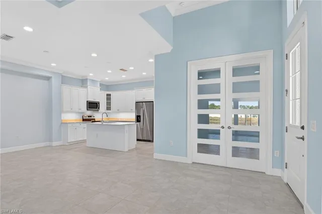 a view of an empty room with kitchen view