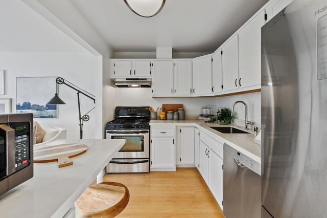 a kitchen with stainless steel appliances a stove a sink and white cabinets