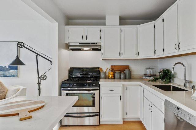 a kitchen with white cabinets and appliances