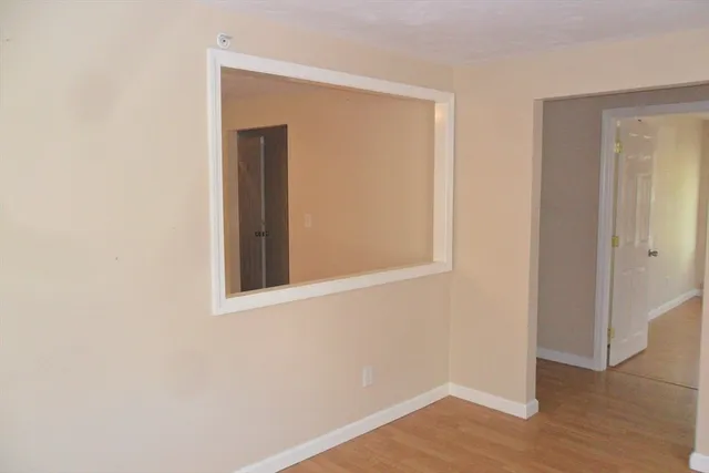 a view of an empty room with wooden floor and closet