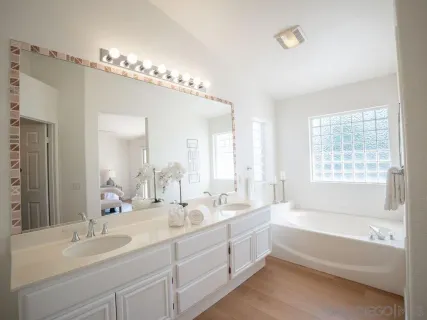 a bathroom with a double vanity sink large mirror and a bathtub