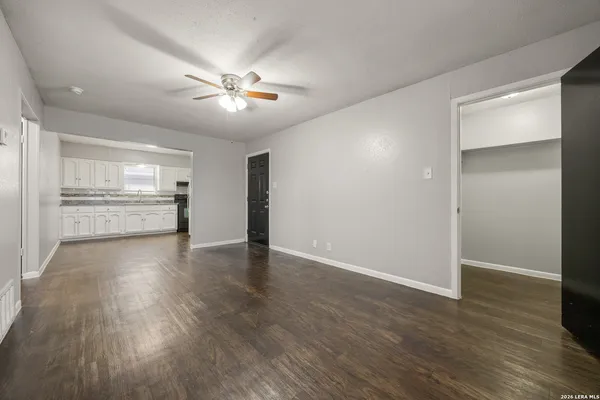 a view of an empty room with window and wooden floor