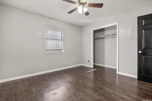 an empty room with wooden floor closet and windows