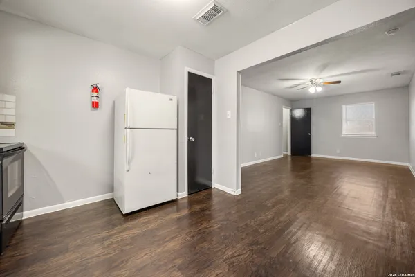 a view of a livingroom with wooden floor and a refrigerator