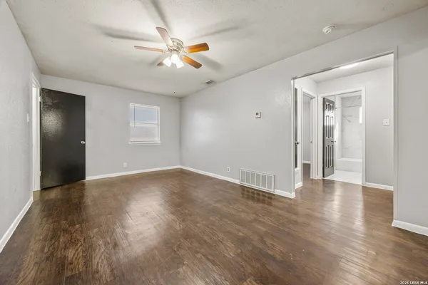 an empty room with wooden floor fan and windows