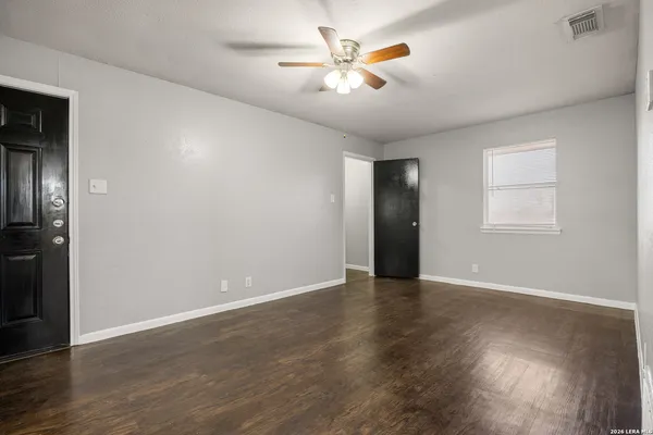 an empty room with wooden floor and a ceiling fan