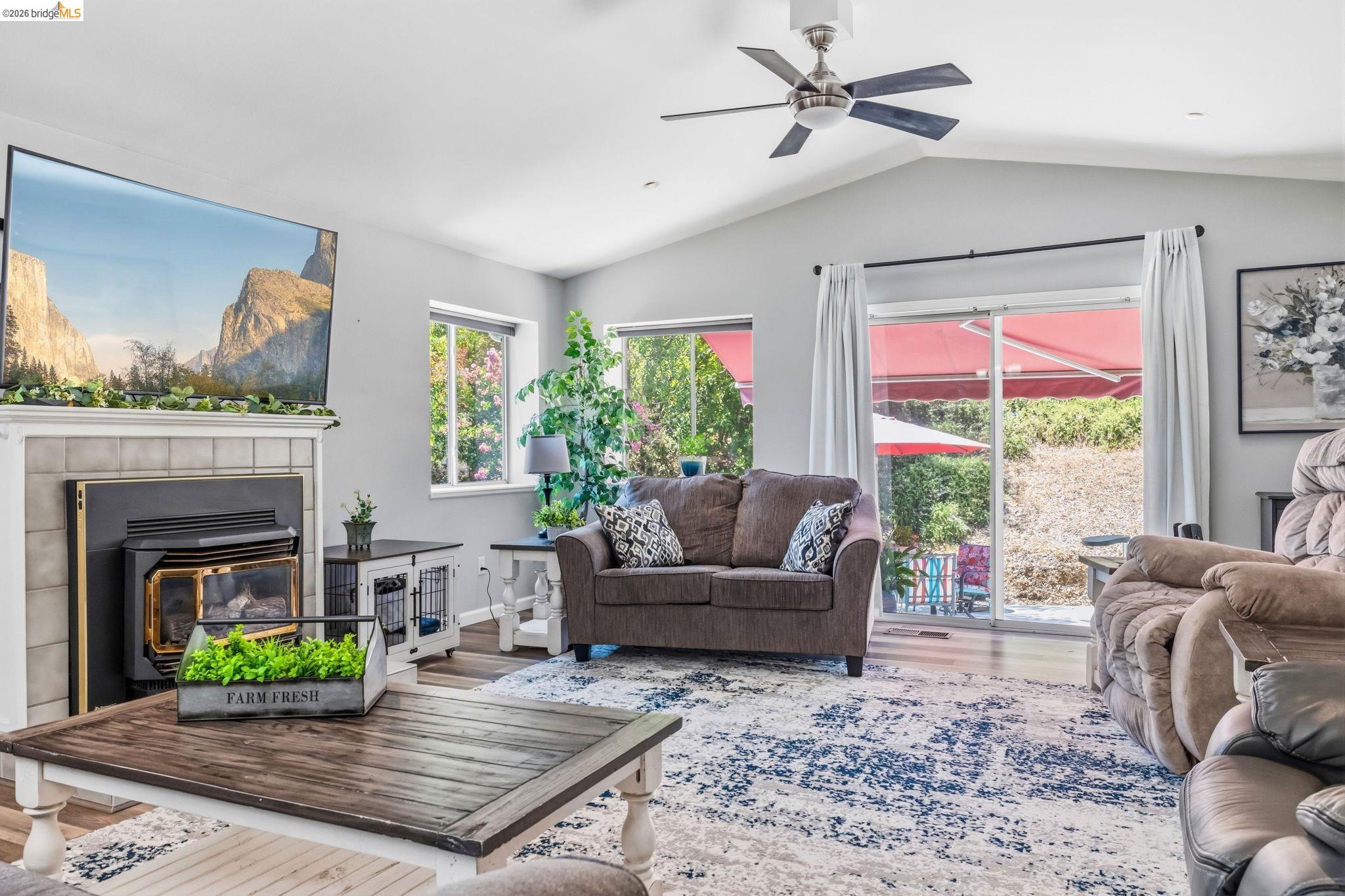 18570 Pradera Real Road Sonora, CA 95370 - Photo 49 of 66 Vaulted ceiling with a ceiling fan, gas fireplace, laminate flooring, multiple recessed windows, and a sliding glass door to the back patio