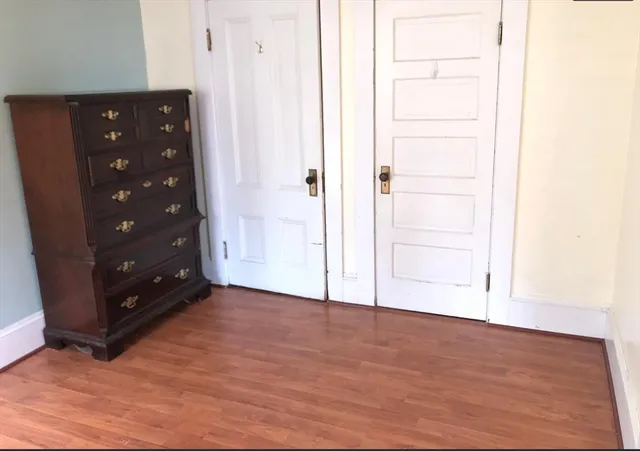 a view of an empty room with wooden floor and a bathroom
