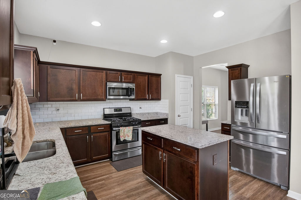 3495 Zaks Way Bethlehem, GA 30620 - Photo 13 of 40 a kitchen with stainless steel appliances granite countertop a stove top oven a sink and dishwasher a refrigerator with wooden floor
