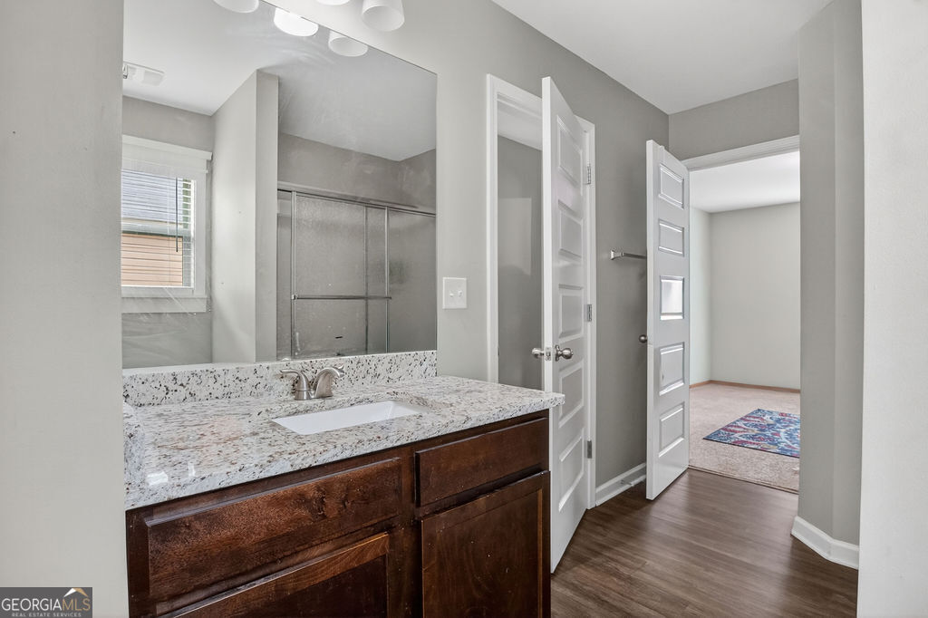 3495 Zaks Way Bethlehem, GA 30620 - Photo 28 of 40 a bathroom with a granite countertop sink a mirror and a shower