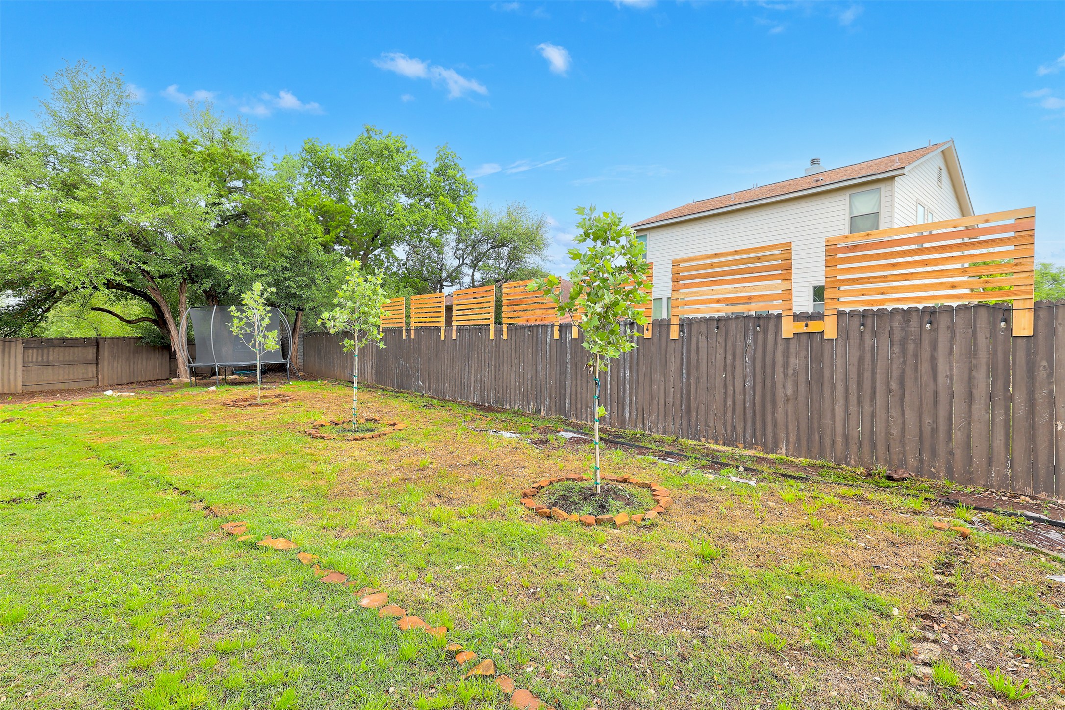 117 Rock Dock Road Georgetown, TX 78633 - Photo 35 of 39 The property features an extensive lawn area, a dark wooden privacy fence with lighter wood trellis accents, mature trees plus 3 newly planted trees...