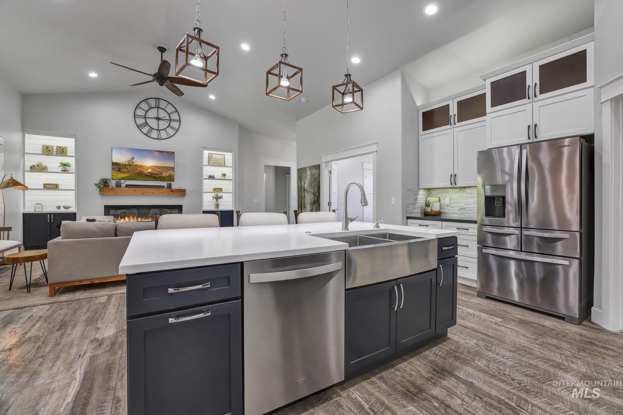 1937 Tamarack Loop Twin Falls, ID 83301 - Photo 15 of 50 Open-concept living space featuring wood-finish flooring, a kitchen island with a stainless steel farmhouse sink, a stainless steel dishwasher, and dark cabinetry