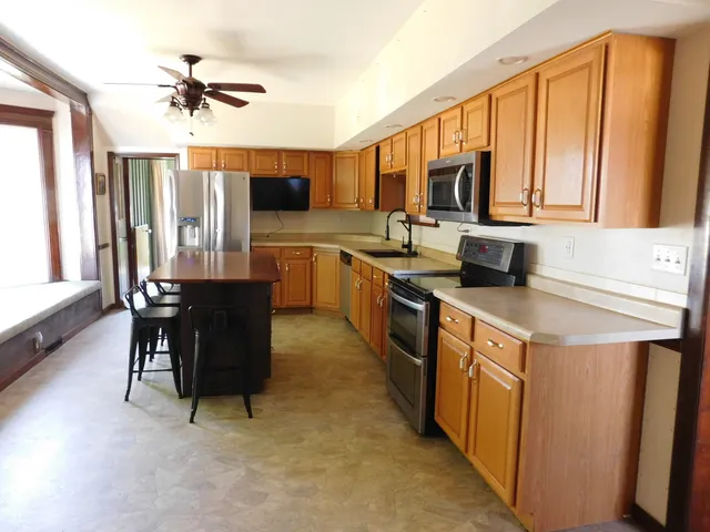 a kitchen with stainless steel appliances granite countertop a stove top oven a sink dishwasher and a dining table with cabinets