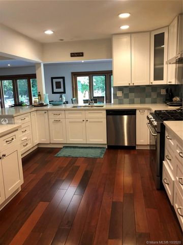 a white kitchen with wooden floors and white walls