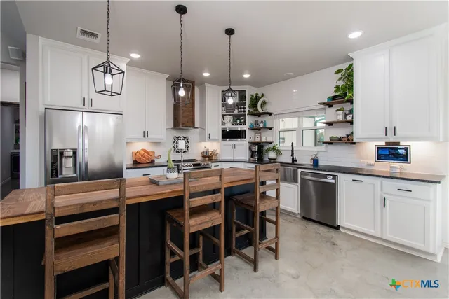 a kitchen with kitchen island granite countertop a sink a counter space appliances and cabinets