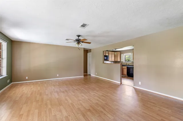 a view of an empty room with a window and wooden floor
