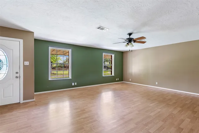 a view of an empty room with window and wooden floor