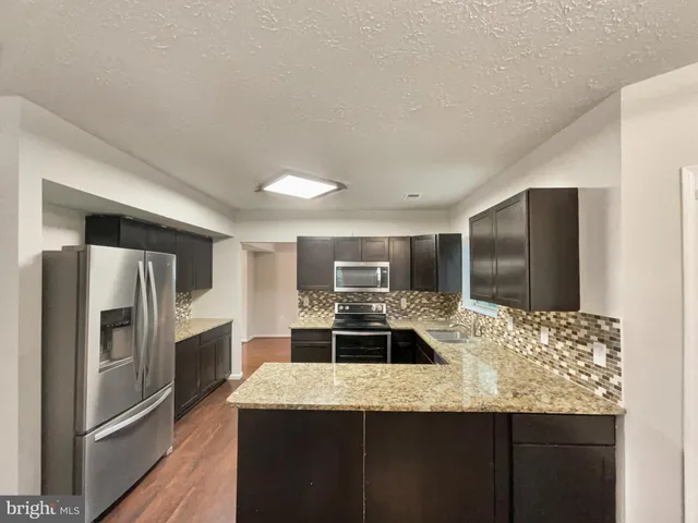a kitchen with stainless steel appliances granite countertop a sink and a refrigerator