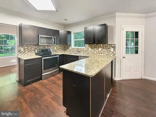 a kitchen with stainless steel appliances kitchen island granite countertop a sink and a stove