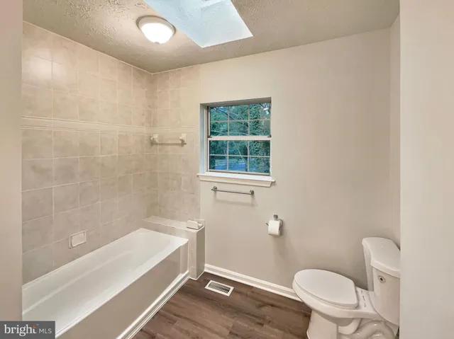 a bathroom with a granite countertop bathtub a toilet and a shower