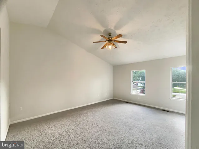 an empty room with windows and chandelier fan