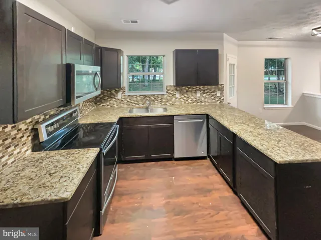 a kitchen with stainless steel appliances granite countertop sink stove top oven and granite counter top