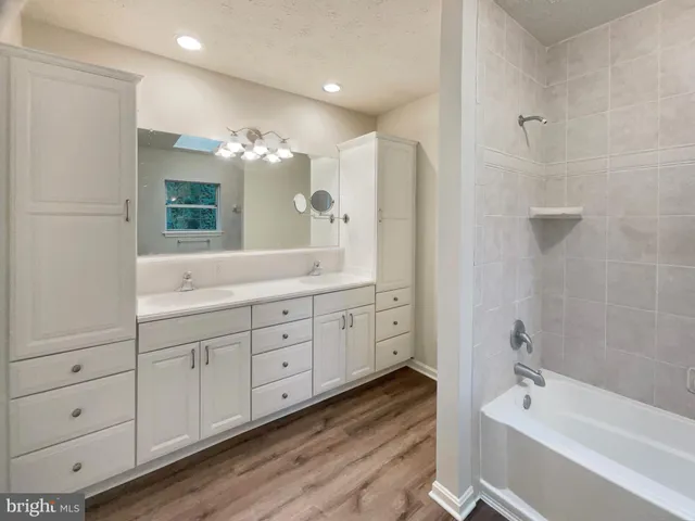 a spacious bathroom with double vanity a large mirror and a bathtub