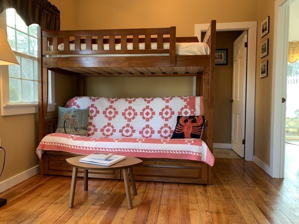 11 Hughes Road, Unit 1 Truro, MA 02666 - Photo 8 of 35 a bed sitting in a bedroom next to a window with wooden floor