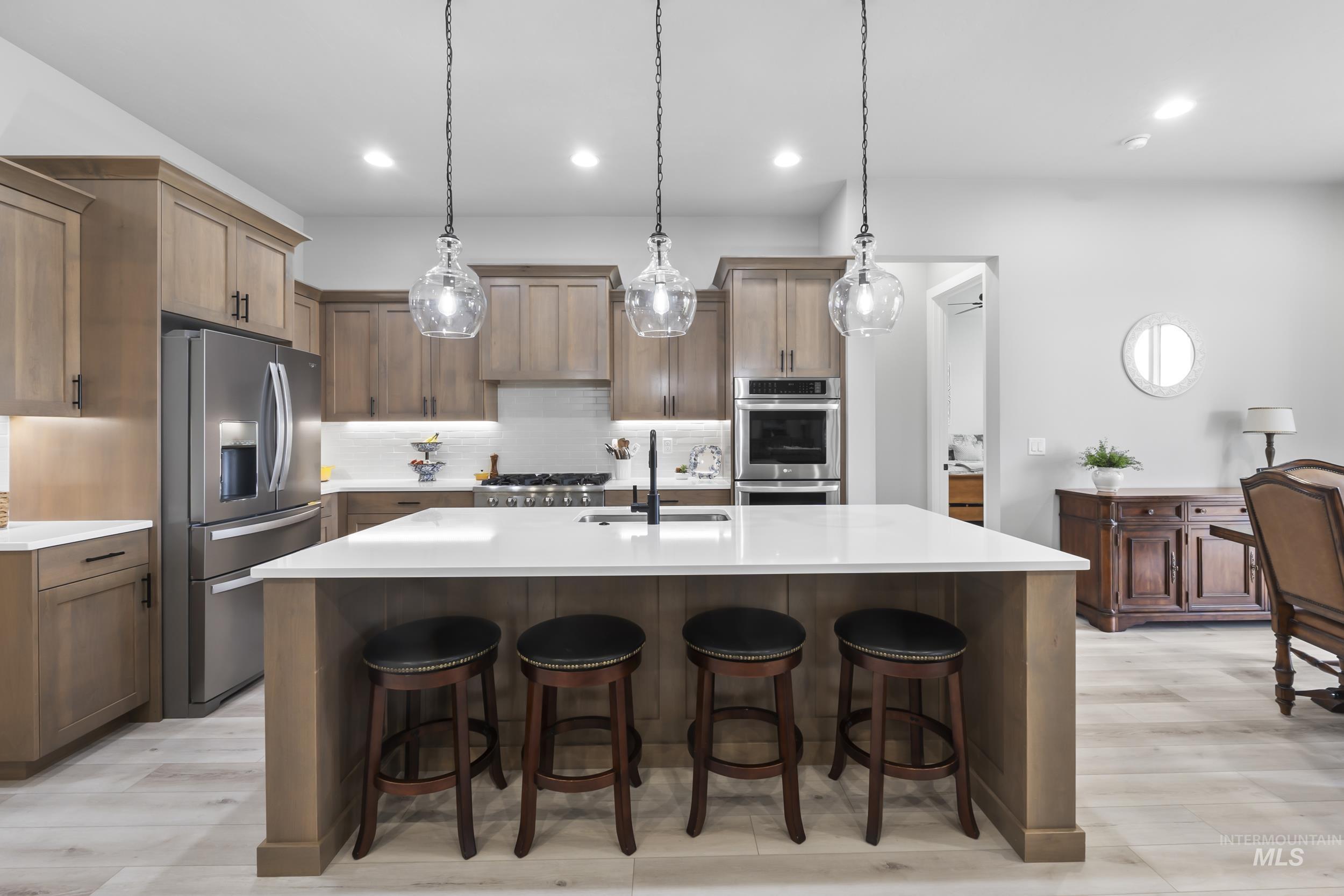 24696 Regal Road Middleton, ID 83644 - Photo 3 of 24 Kitchen with a kitchen bar, stainless steel appliances, light wood-type flooring, and pendant lighting