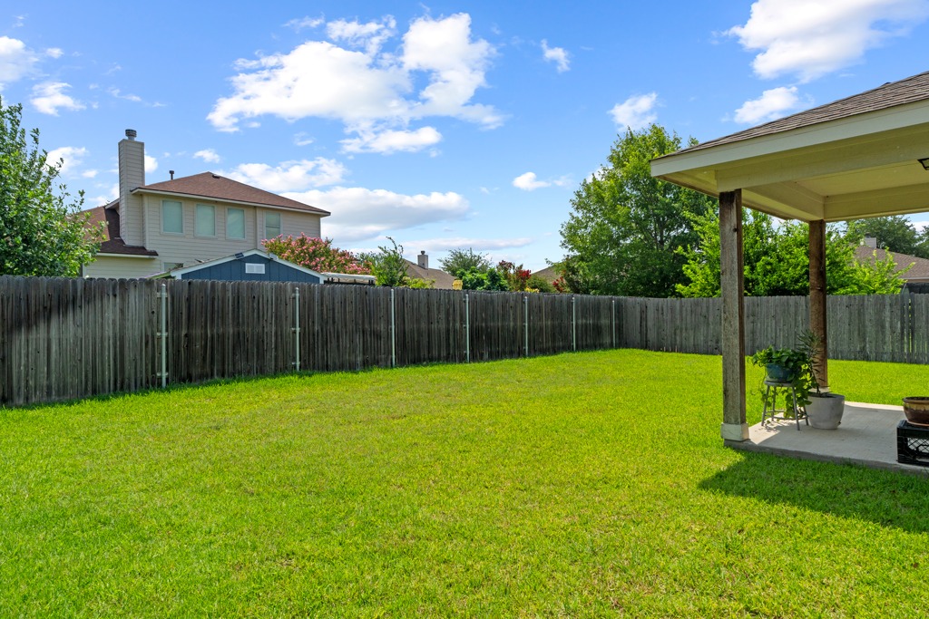12008 Lansdowne Road Austin, TX 78754 - Photo 26 of 29 Green yard enclosed by a fence offers a serene private outdoor space with a covered patio.