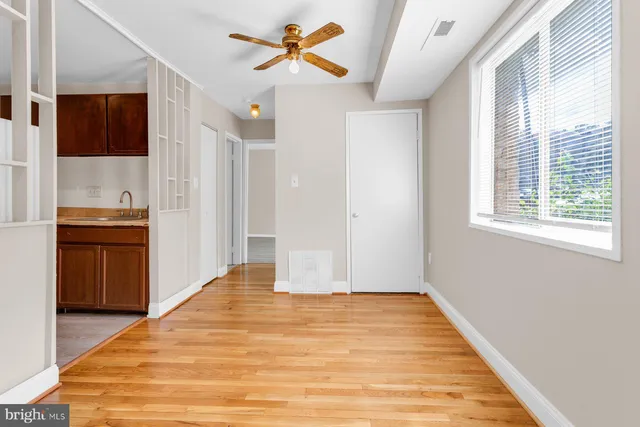 a view of empty room with wooden floor and fan