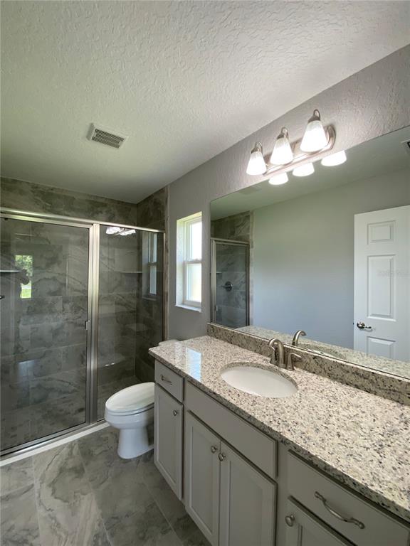 15298 Southwest 43rd Court Ocala, FL 34473 - Photo 21 of 26 a bathroom with a granite countertop sink a toilet and shower