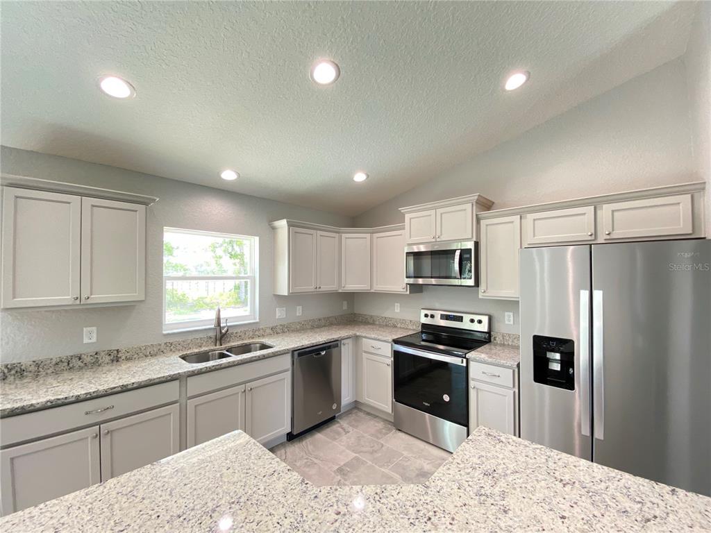 15298 Southwest 43rd Court Ocala, FL 34473 - Photo 6 of 26 a kitchen with granite countertop a refrigerator sink and stove