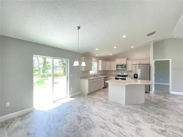 a large white kitchen with a large window and stainless steel appliances