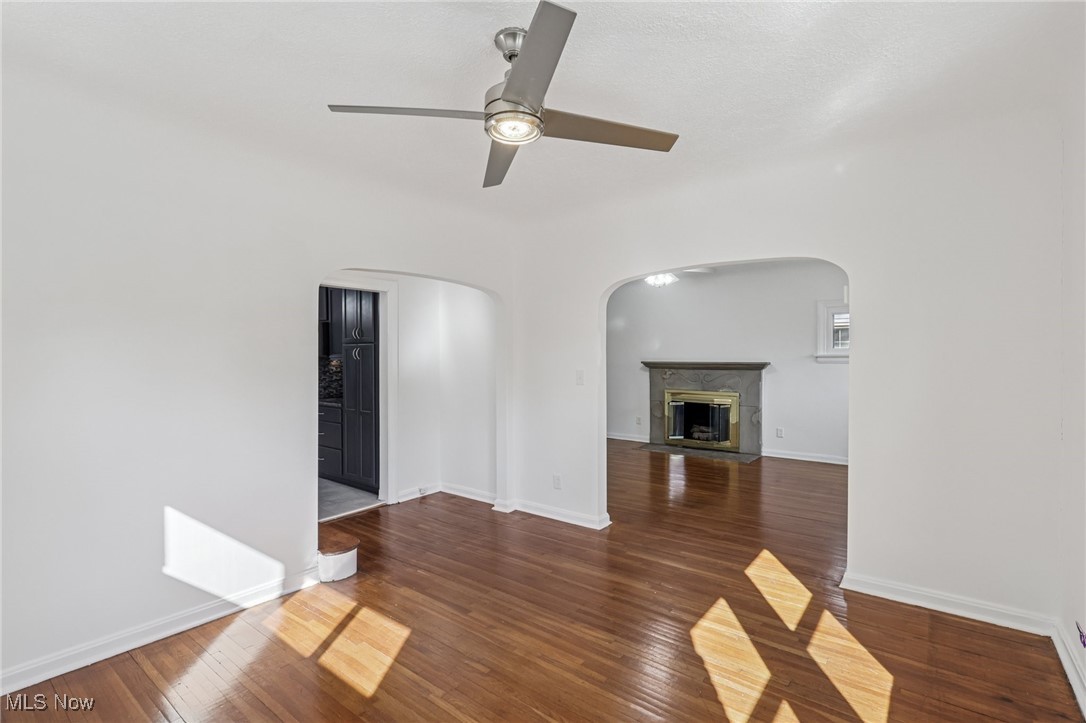 3621 Cedarbrook Road Cleveland, OH 44118 - Photo 12 of 40 Unfurnished living room with dark wood-type flooring, a high end fireplace, arched walkways, and a ceiling fan