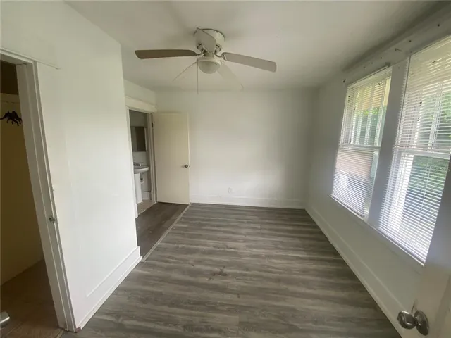 a view of empty room with wooden floor and fan