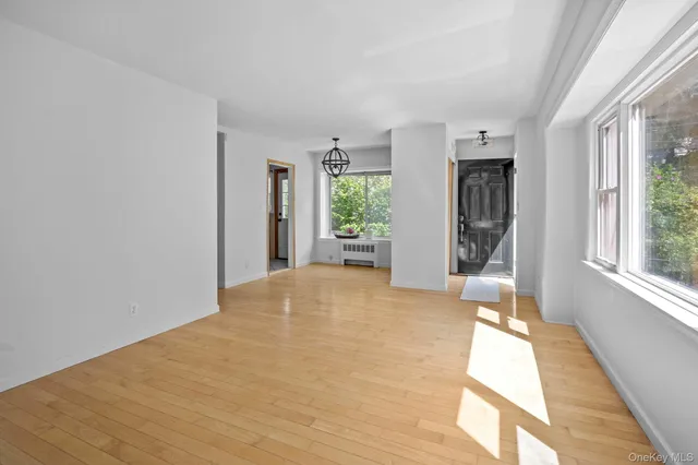 a view of an empty room with window and wooden floor