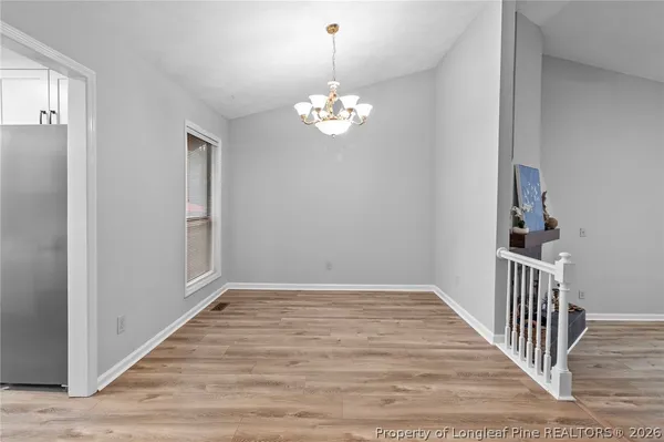 a view of an empty room with chandelier fan and wooden floor