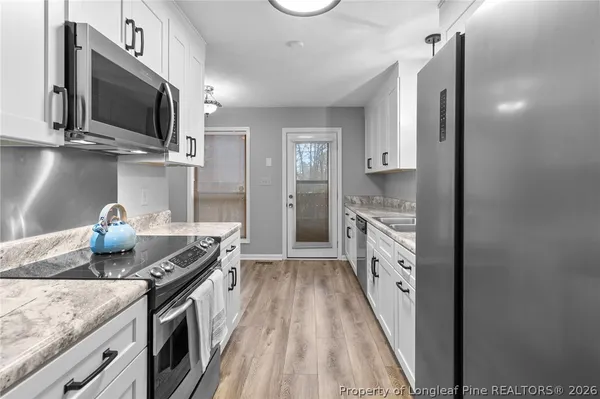 a kitchen with granite countertop stainless steel appliances a sink stove top oven and microwave